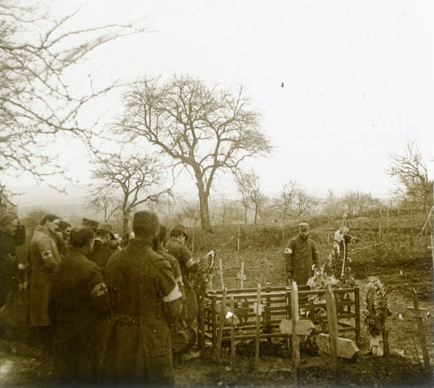 Un groupe de soldats rend un dernier hommage à l’un des leurs autour d’une tombe fleurie. Collection de plaques de verre stéréoscopiques de Maurice Brun, musicien au 89e RI. Sans date. Archives nationales, 700AP/13/PA_341/1
